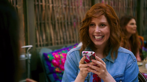 a red haired woman on her phone writing an instagram caption